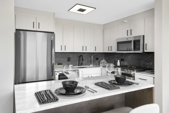 a kitchen with a white counter top and a stainless steel refrigerator