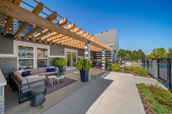 A patio area with a wooden pergola and seating area.
