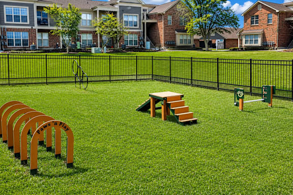 A playground with a slide, swings, and a seesaw in a grassy area.
