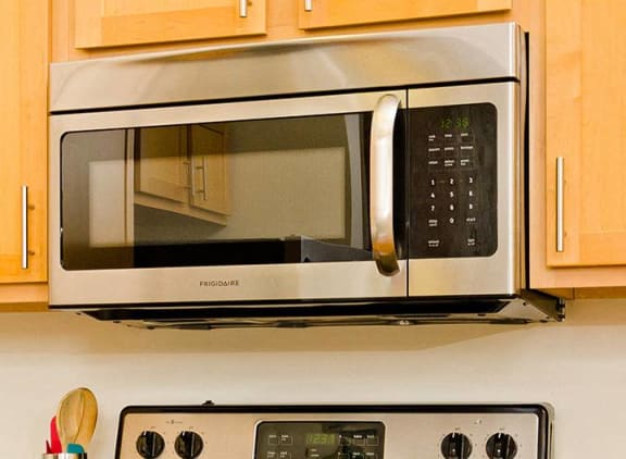 a silver microwave oven sitting on top of a stove