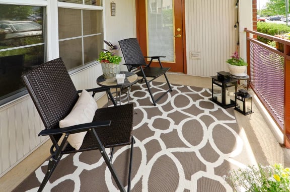 a patio with two chairs and a rug