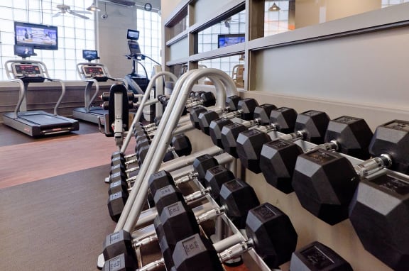 a spacious fitness center with cardio equipment and large windows