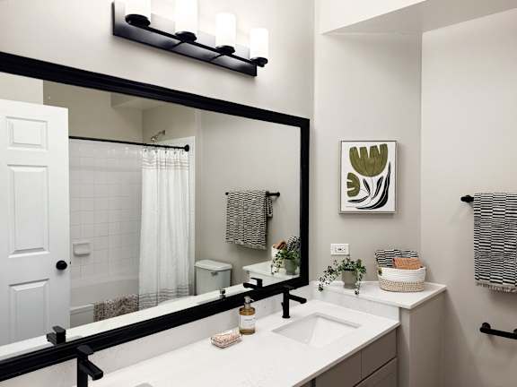 A bathroom with a white sink and a large mirror.