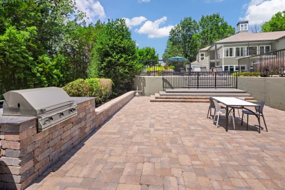 a patio with a barbecue grill and a table and chairs