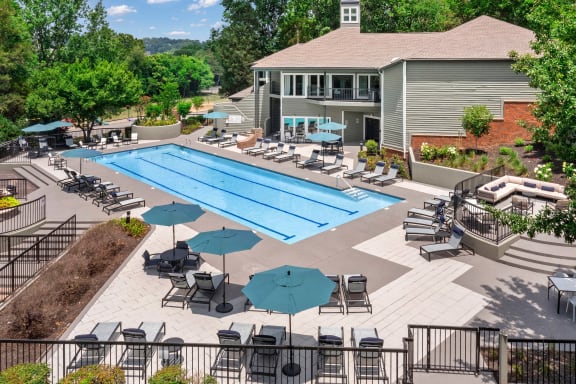 a swimming pool with lounge chairs and umbrellas in front of a building
