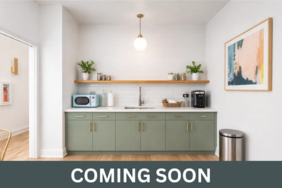 A kitchen with a counter, microwave, and cabinets is coming soon.