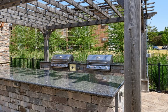 an outdoor kitchen with a stone wall and a pergola