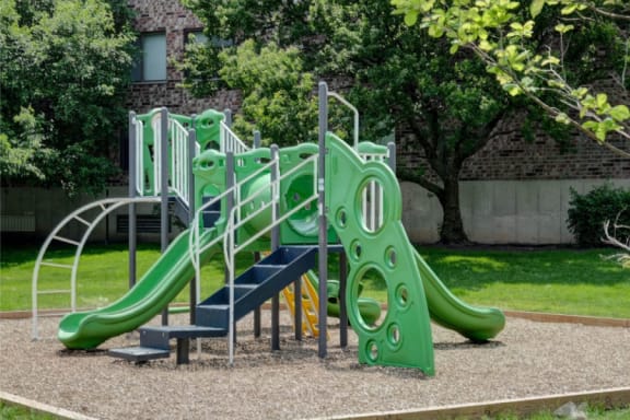 a playground with a green slide and stairs