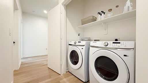 Two white front loading washing machines in a laundry room.