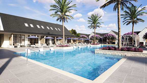 A large swimming pool surrounded by palm trees and a building with a black roof.