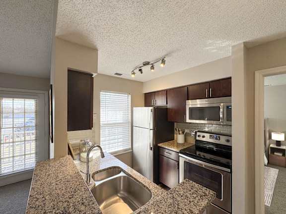 A kitchen with a sink, stove, and refrigerator.