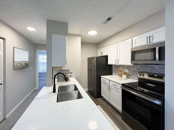A modern kitchen with black appliances and white countertops.