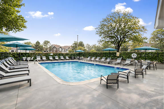 A large outdoor swimming pool surrounded by lounge chairs and umbrellas.