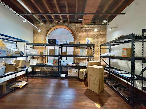 A warehouse with boxes on the floor and shelves.