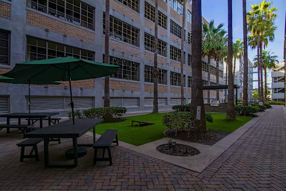 A patio with a table and benches is surrounded by a brick wall and palm trees.