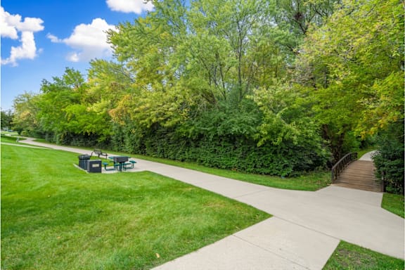 A park with a paved walkway and a picnic table.