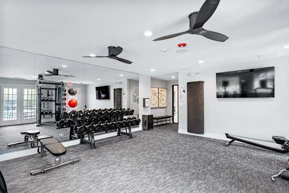 A gym with a variety of equipment including weights and a bench.