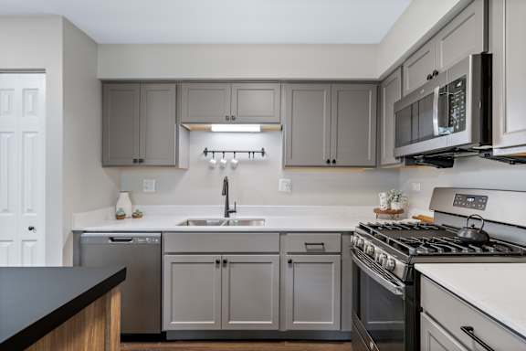 A kitchen with a white stove top oven and a white dishwasher.