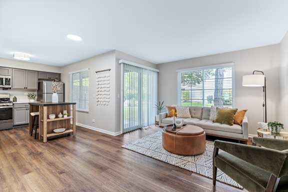 A well-lit, spacious living room with a kitchen area in the background.