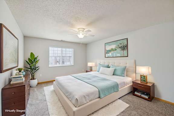 A bedroom with a bed, nightstand, and a plant.
