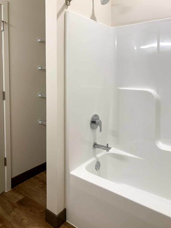 a white tub and shower next to a storage space with built in shelves