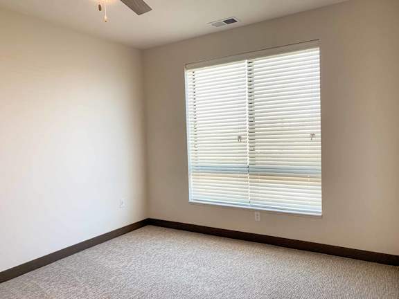 a bedroom with a large window and ceiling fan