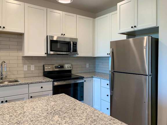 a kitchen with white cabinets and a stainless steel refrigerator