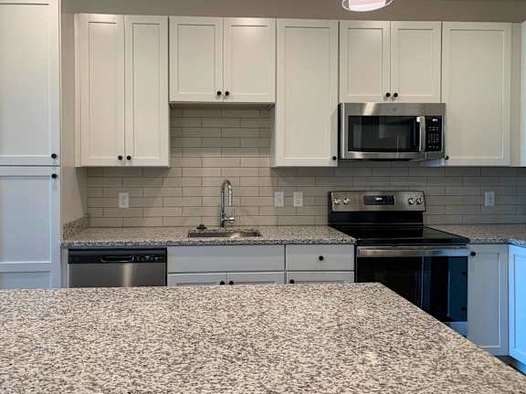 a kitchen with white cabinets, stainless steel appliances, and granite countertops