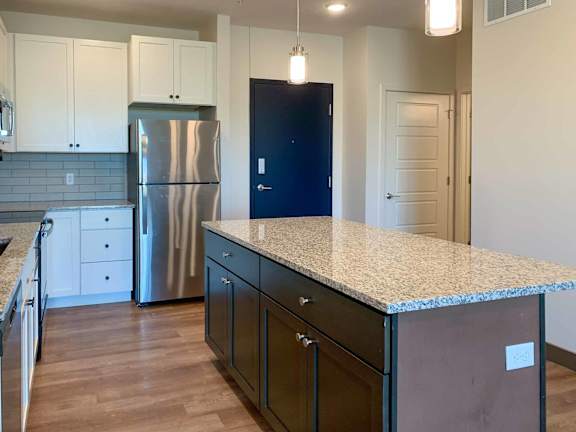 a kitchen with a large island with a granite counter top