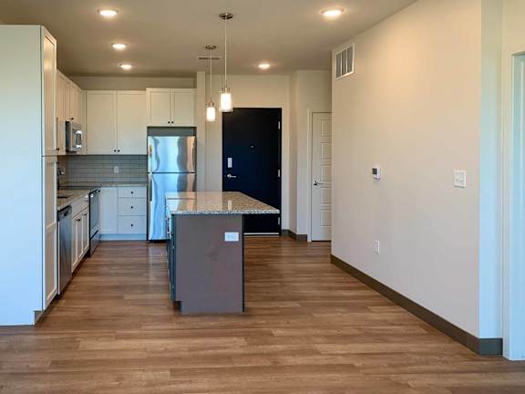 a kitchen with white cabinets, granite counter tops, and hardwood floors