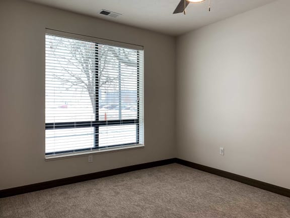 a bedroom with a large window and ceiling fan