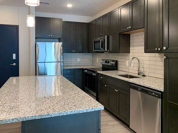 a kitchen with granite counter tops and dark cabinets