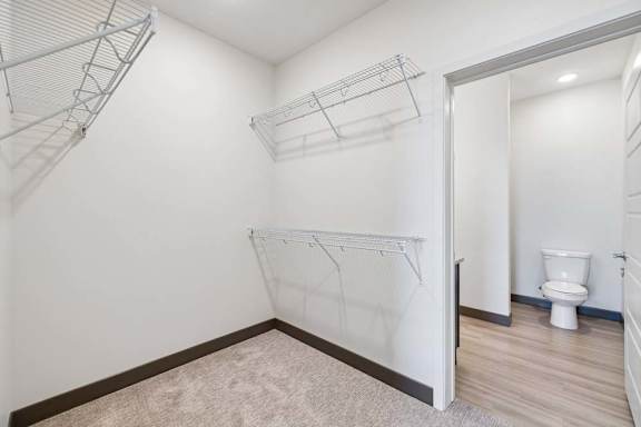 Walk-in closet with multiple wire shelving racks and direct access to an adjoining bathroom.