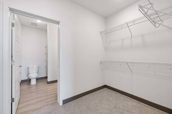 Walk-in closet with wraparound wire shelving and direct access to the adjoining bathroom.