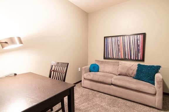 A room with a couch, chair, and a picture on the wall.