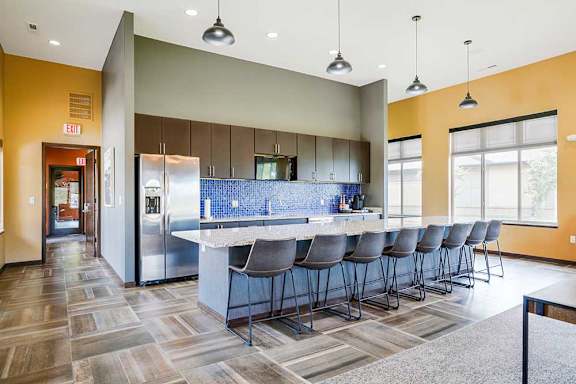 A kitchen in the clubhouse with an oversized island and several barstools.
