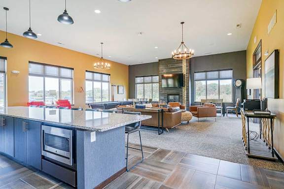 A modern TV lounge with leather couch and chairs, a pool table, a printing station, and a kitchen with large island for hosting gatherings.
