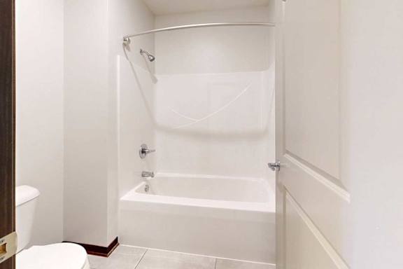 A bathroom with a white tub shower with a curved curtain rod.