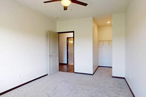 A bedroom with a ceiling fan, and an open walk-in closet.
