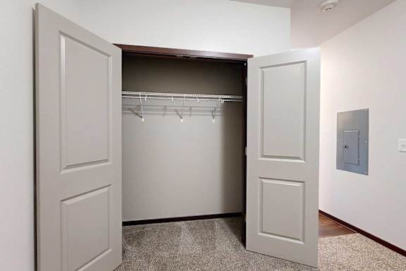 A den space with a carpeted floor and a double door closet, perfect for an at home office.