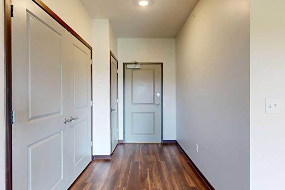 A hallway leading from the front door to the kitchen, with two closets on the left.