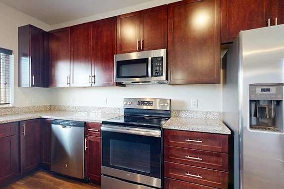 A modern kitchen with dark wood cabinets and stainless steel appliances.