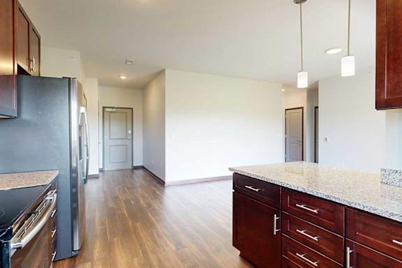 A kitchen with dark wood cabinets and a granite countertop peninsula.