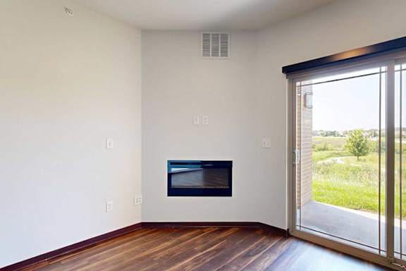 A living room with hardwood flooring, an electric fireplace, and a sliding glass door to a patio.