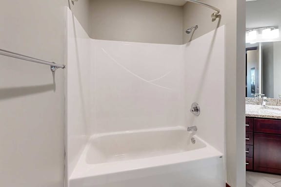 A white tub shower with a curved curtain rod, and a towel bar.