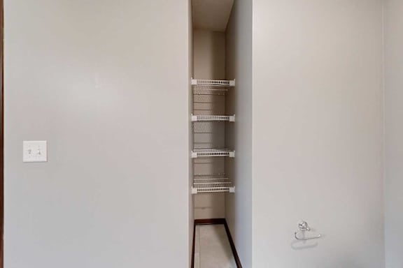 A bathroom with an inlet with built-in shelves for linen storage.