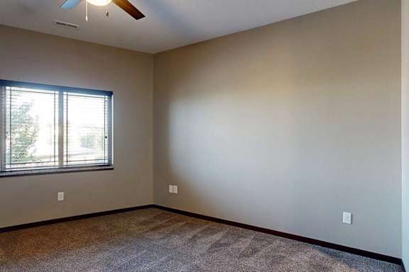 A bedroom with a window and a ceiling fan.