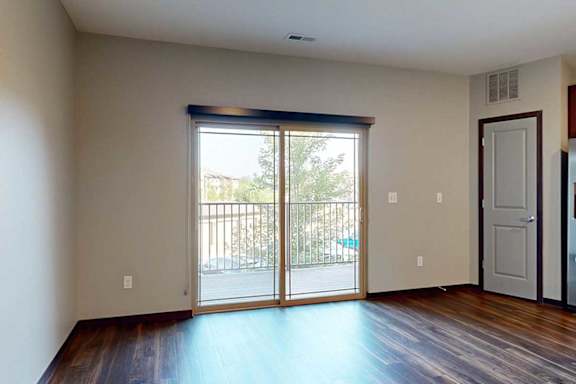 A living room with a sliding glass door to a balcony with a roller shade.