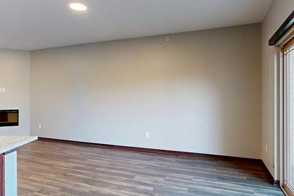 A living room with hardwood flooring, an electric fireplace, and a sliding glass door to a balcony.
