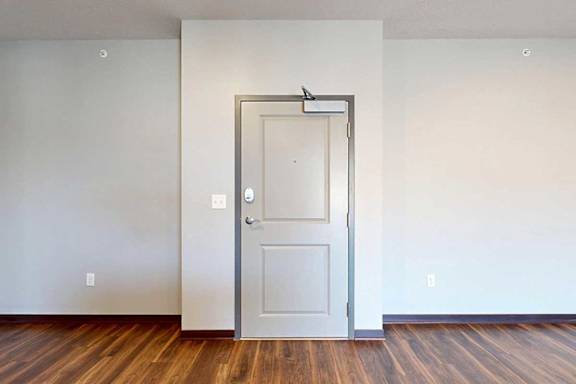 A light grey front door to the apartment with a slight bump in for the hallway recess.